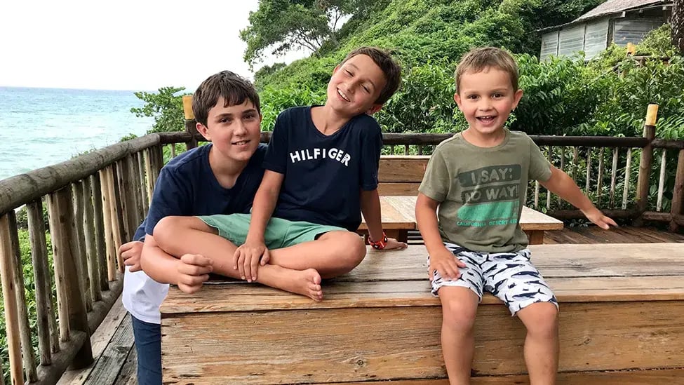 Drei Jungs sitzen auf der Veranda eines Feriendomizils mit Meerblick