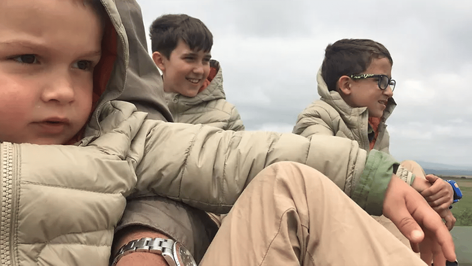 Drei Jungs sitzen bei einer Safari auf einem Jeep
