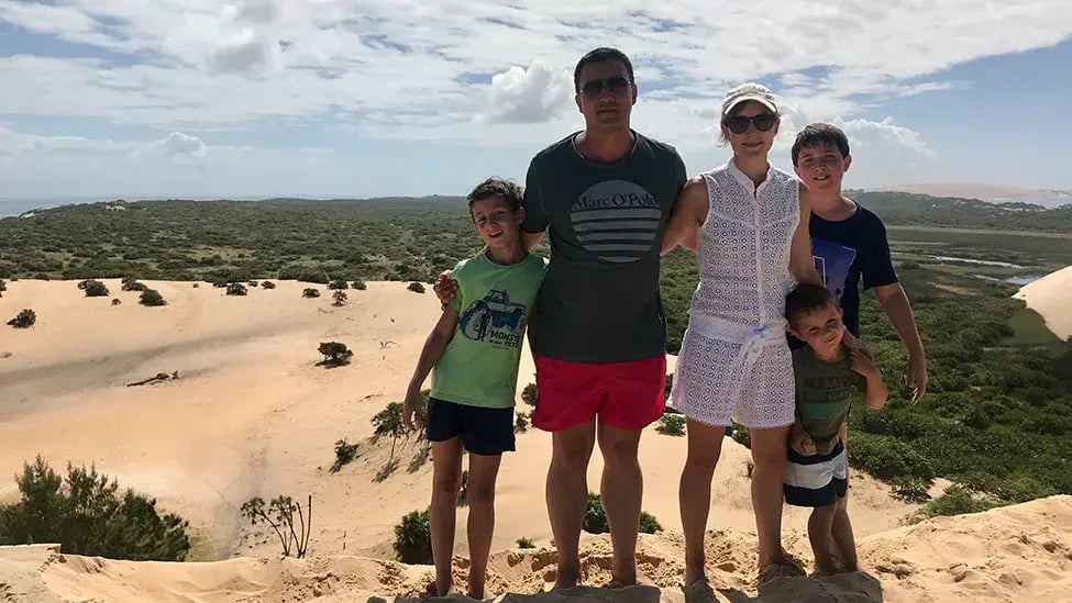 Eltern mit drei Söhnen stehen auf einer Sanddüne vor einer weiten Landschaft