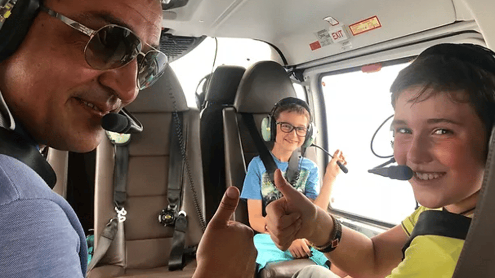 Ein Vater mit seinen zwei Söhnen sitzen angeschnallt in einem kleinen Flugzeug