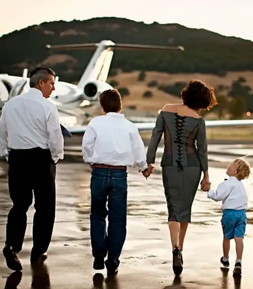 Eltern mit zwei Kindern sind von hinten zu sehen, wie sie auf einen Privatjet zulaufen