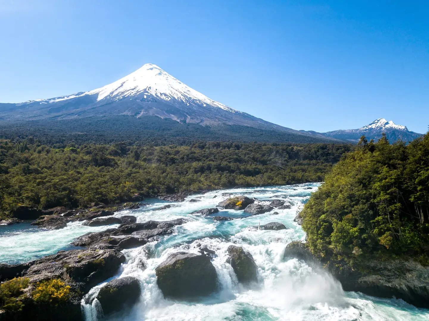 Wasserfall mit schneebedecktem Vulkan im Hintergrund