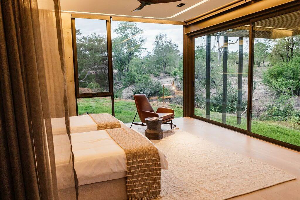 Suite mit Kingsize-Bett, Stuhl und raumhohen Fenstern.