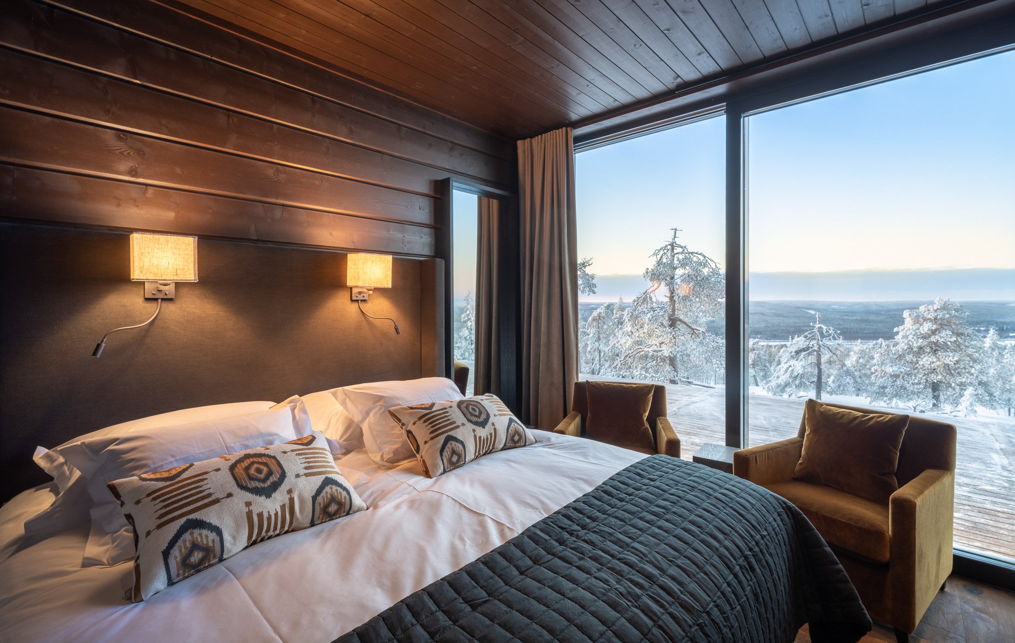 Schlafzimmer mit Panorama Fenster und Blick auf Schneelandschaft