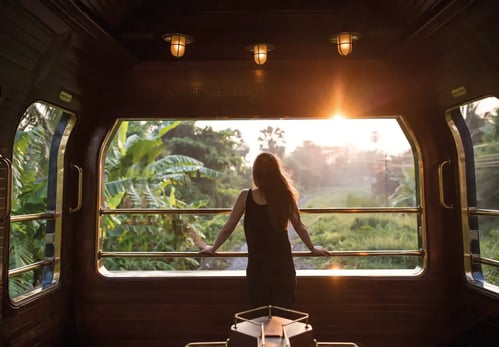 Eine Frau steht am Fenster des Luxuszugs Eastern and Oriental Express in Südostasien und genießt den Ausblick