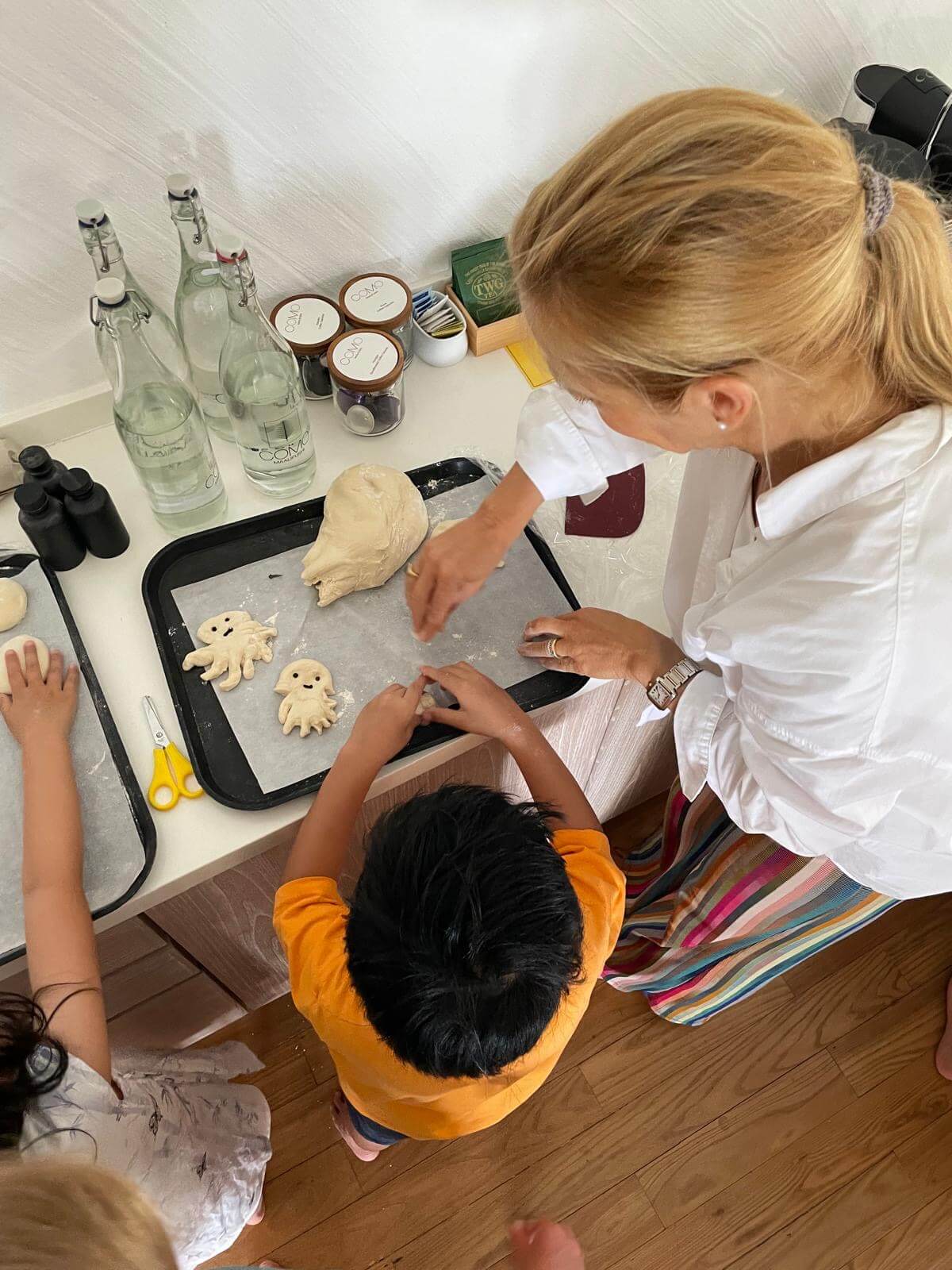 Eine Frau backt mit Kindern Kekse in Form von Tintenfischen.
