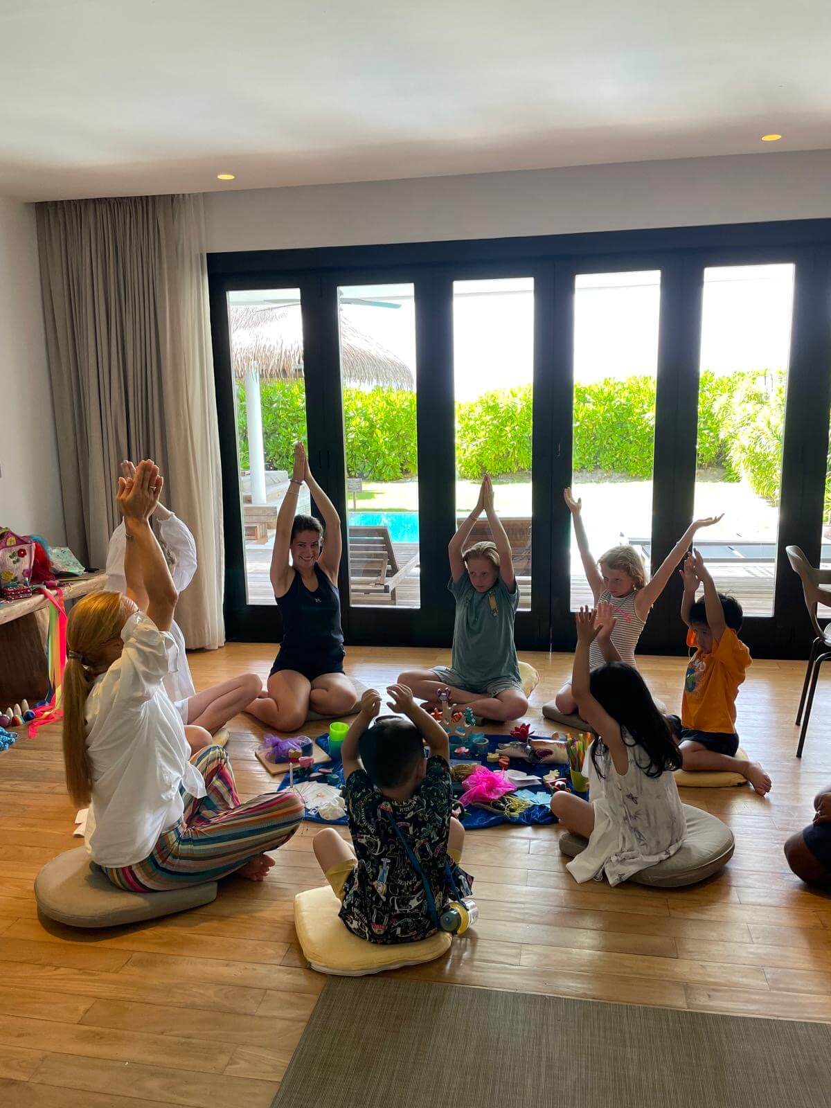 Eine Frau macht mit Kindern im Sitzkreis leichte Yogaübungen.