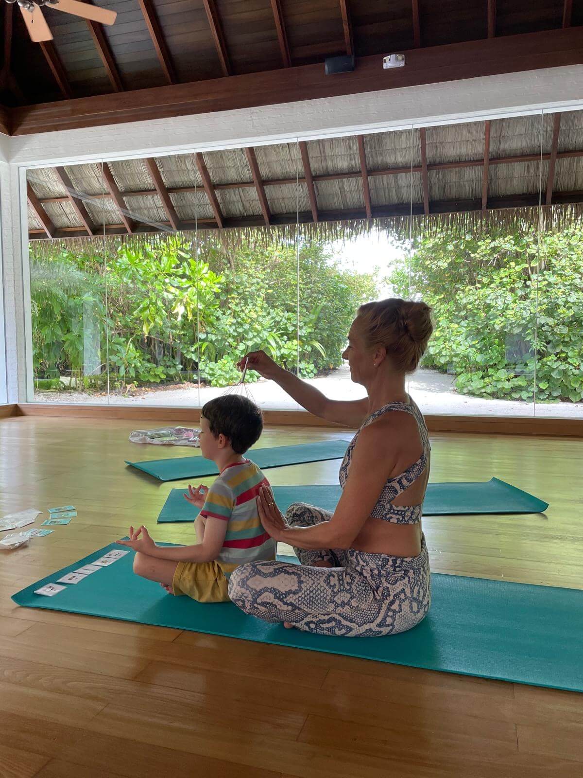 Ein Junge erhält von einer Frau im Rahmen eines Yoga-Workshops eine Kofmassage.