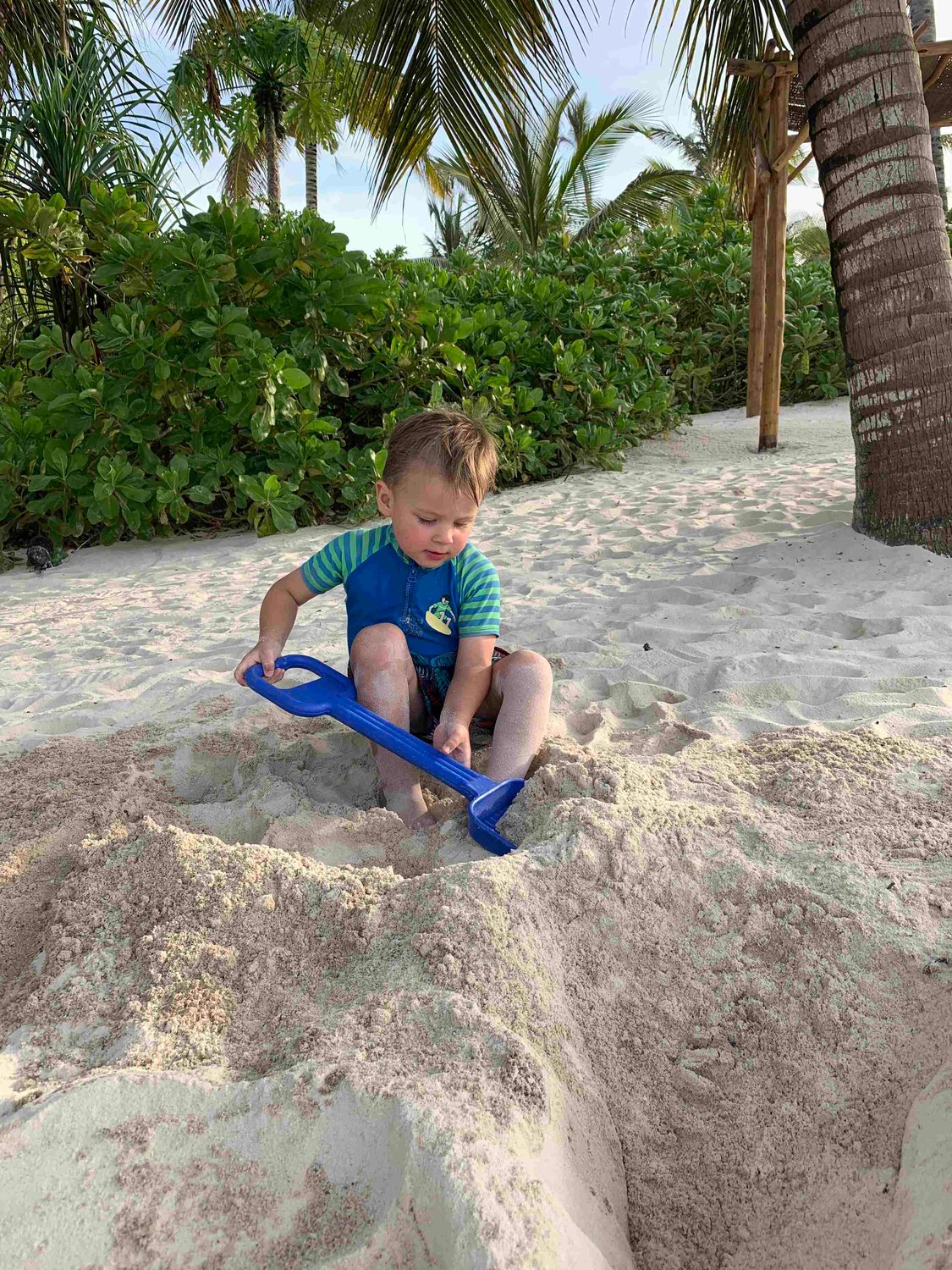Kind spielt im Sand mit einer Schaufel
