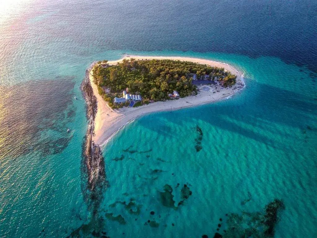 Die kleine Privatinsel Thanda Island in Tansania ist von oben zu sehen. Sie liegt in einem traumhaft blauen Meer.