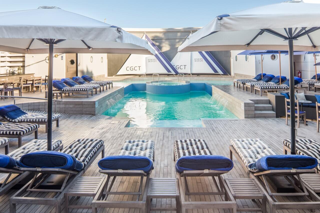 Pool mit vielen Sonnenliegen und Sonnenschirmen.
