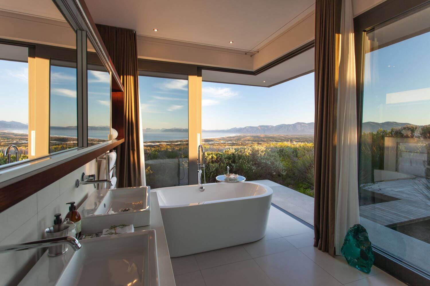 Badezimmer mit Badewanne und raumhohen Fenstern, der Blick geht weit in die Ferne.