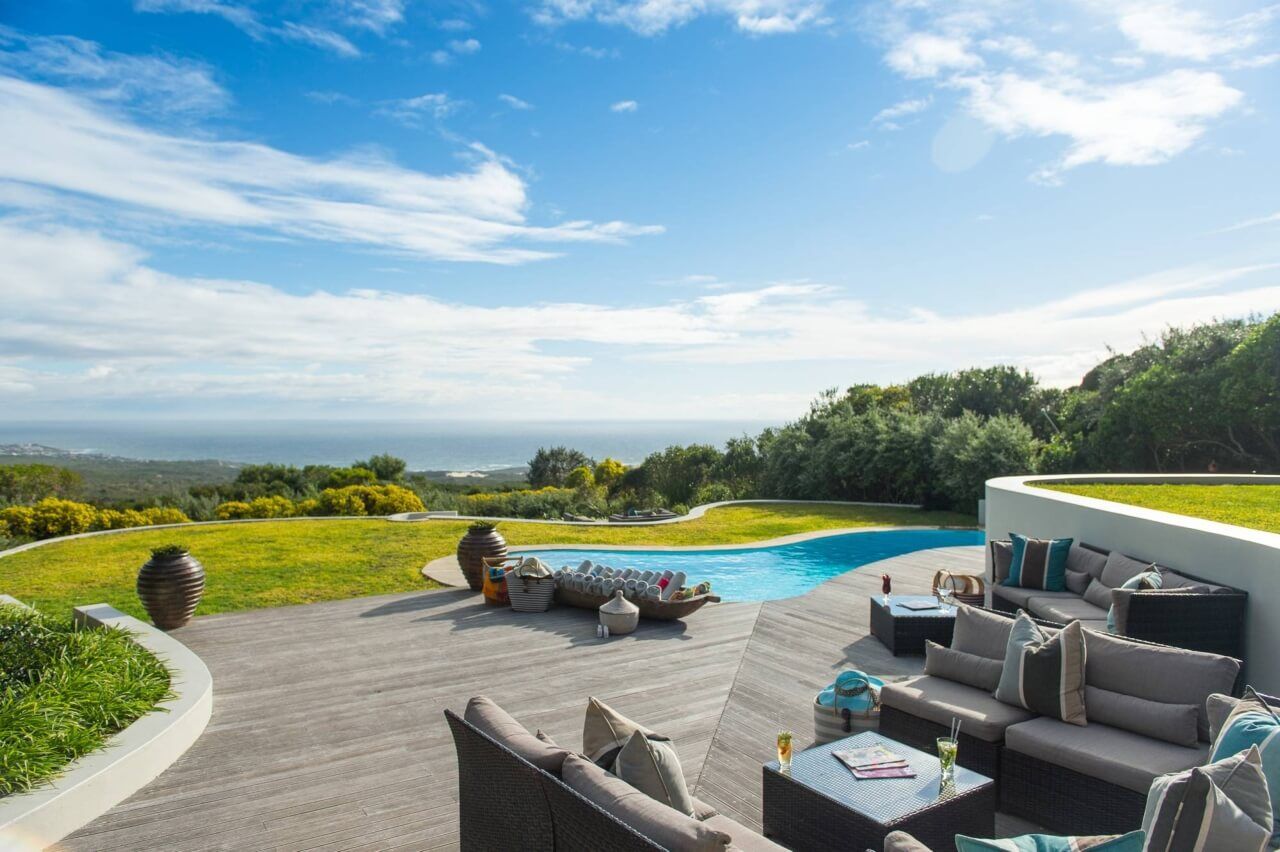 Sonnendeck mit Sitzecken, Liegen und einem Pool im Hintergrund.