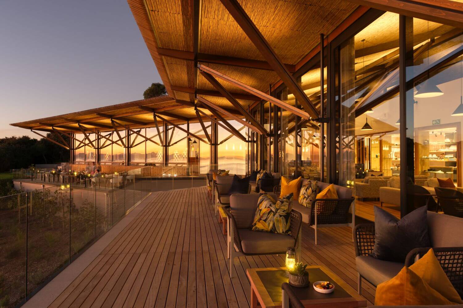 Eine große Terrasse mit vielen Sitzecken in der Abenddämmerung.