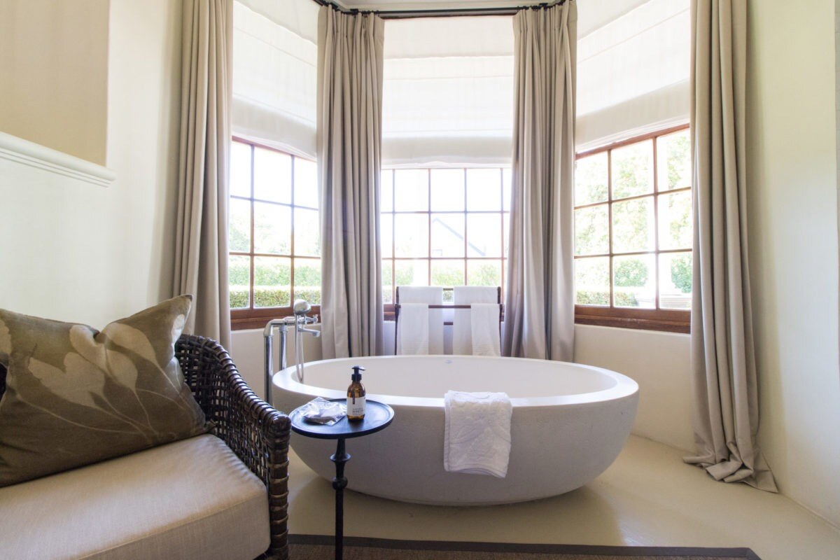 Freistehende weiße Badewanne am Fenster.
