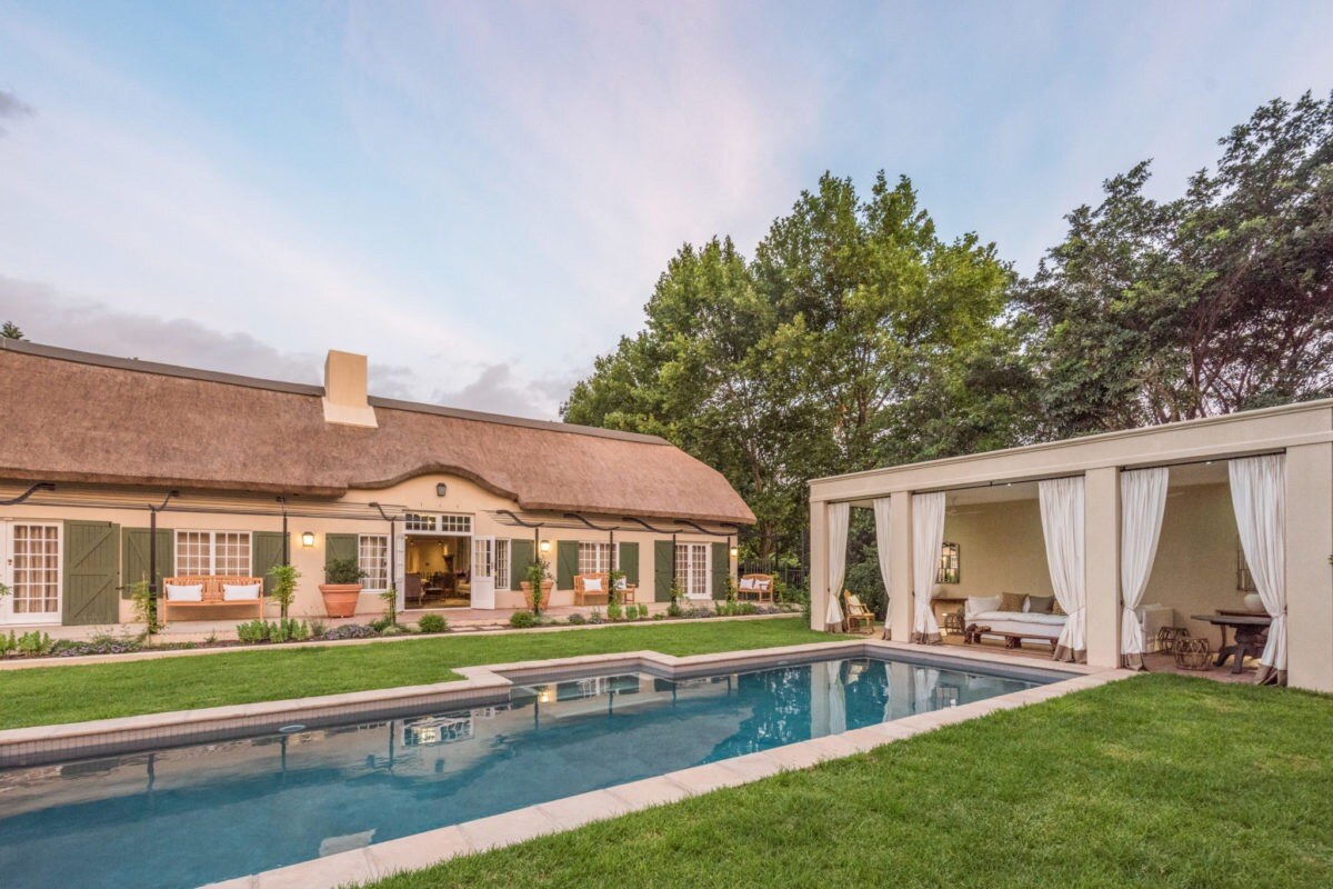 Pool mit Haupthaus und Sonnenlounge im Garten.