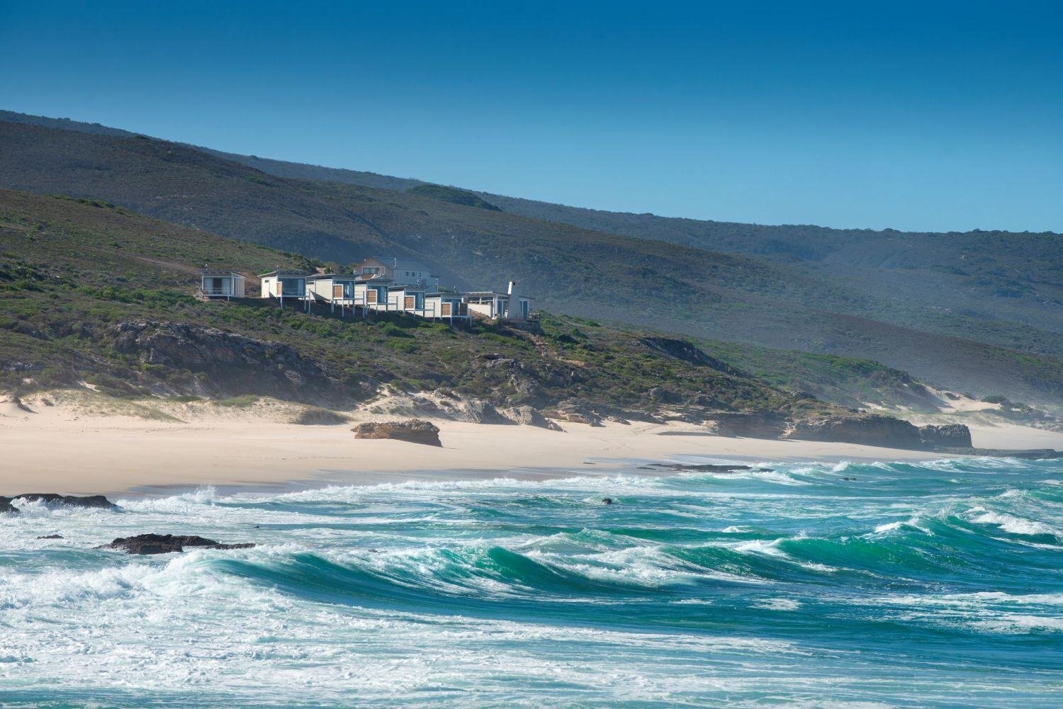 Die Lekkerwater Beach Lodge aus der Ferne abgebildet mit wildem Meer und Küstenstreifen.