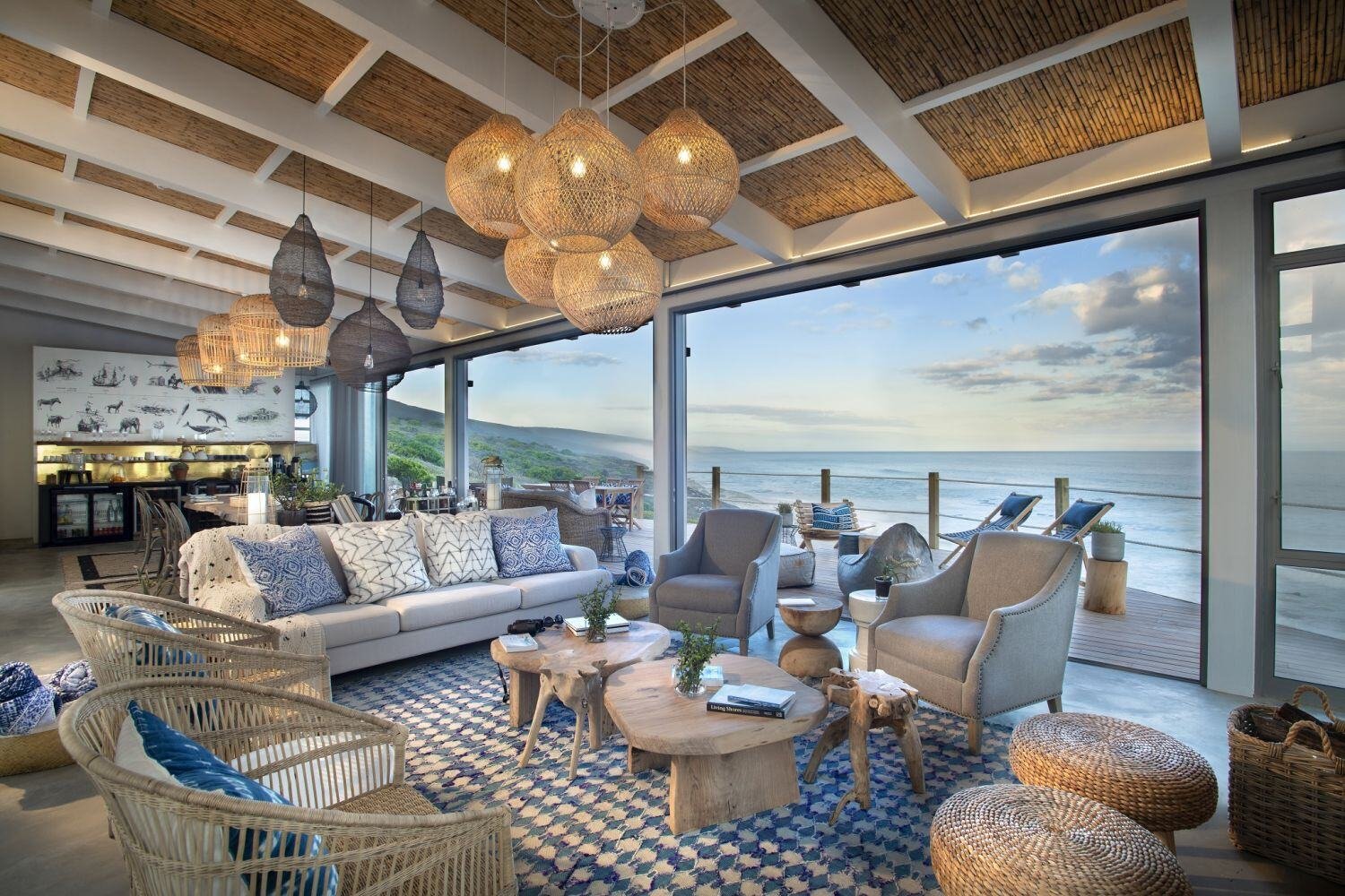 Gemeinschaftsbereich eines Hotels mit Sitzmöbeln. Eine große Fensterfront gibt den Blick auf das Meer frei.