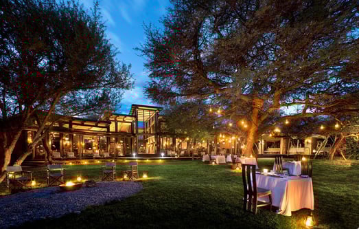 Garten einer Lodge am Abend, überall stehen Laternen, was eine romantische Stimmung erzeugt.