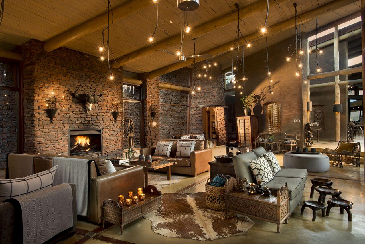 Lounge einer Lodge mit vielen Sitzmöbeln und stylischen Glühbirnen, die von der Decke hängen.