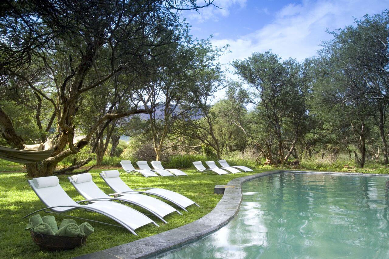 Pool einer Lodge mit Sonnenliegen drumherum.