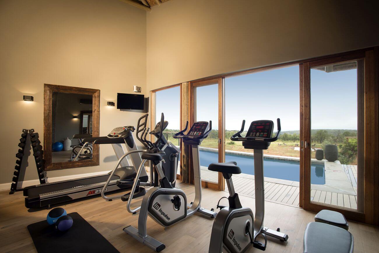 Gym mit verschiedenen Fitnessgeräten und Blick auf den Pool.
