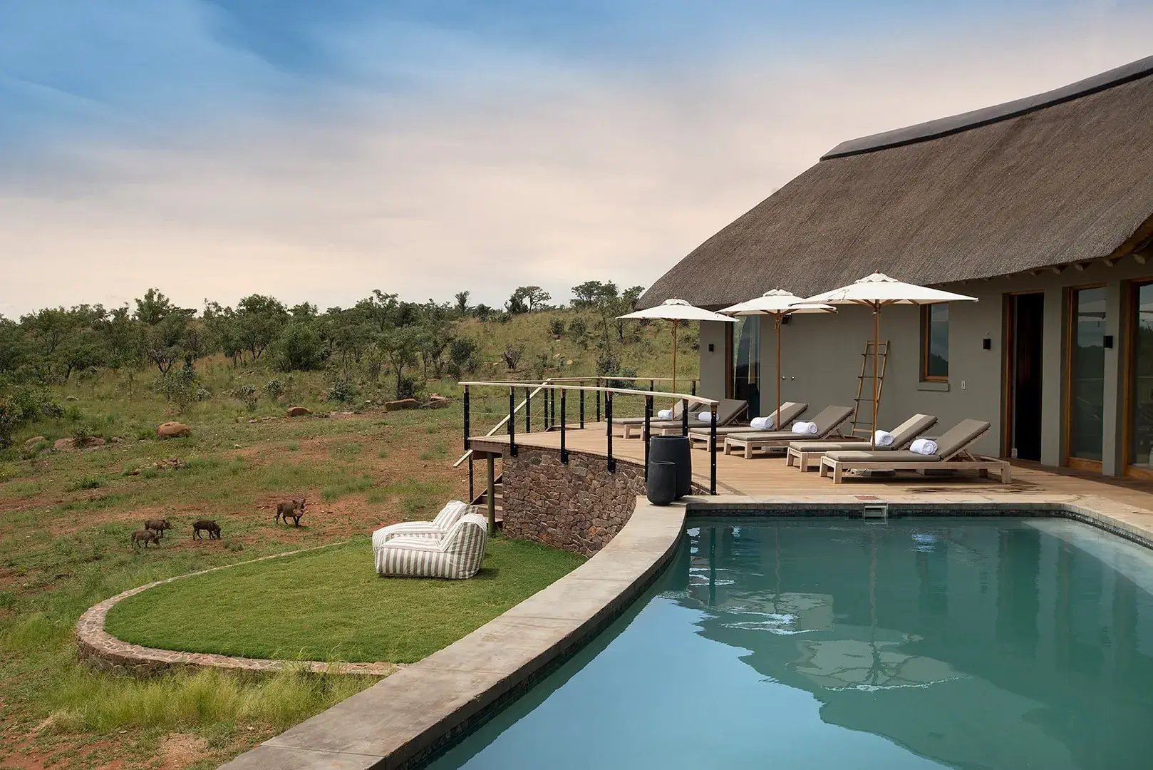 Pool mit Lodge und Blick in die Savanne.