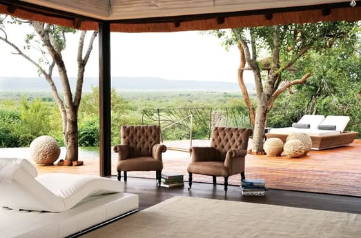 Überdachte Terrasse mit Liegen, Sesseln und Blick in die Natur.