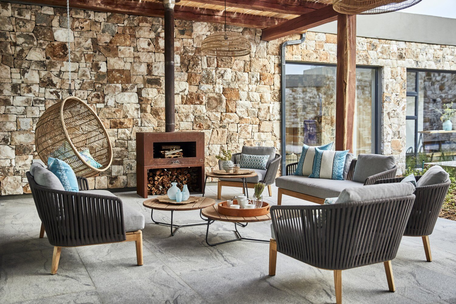 Terrasse mit einem Ofen und grauen Sitzmöbeln.