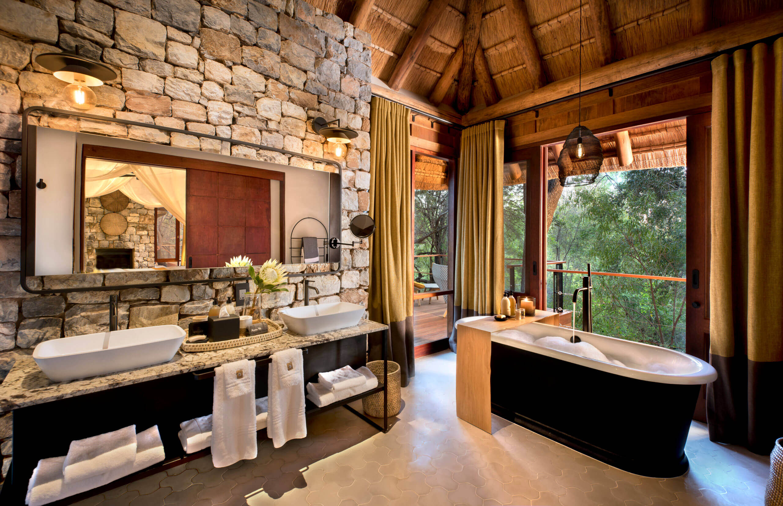 Luxusbadezimmer mit Steinmauer, zwei Waschbecken und einer freistehenden Badewanne.