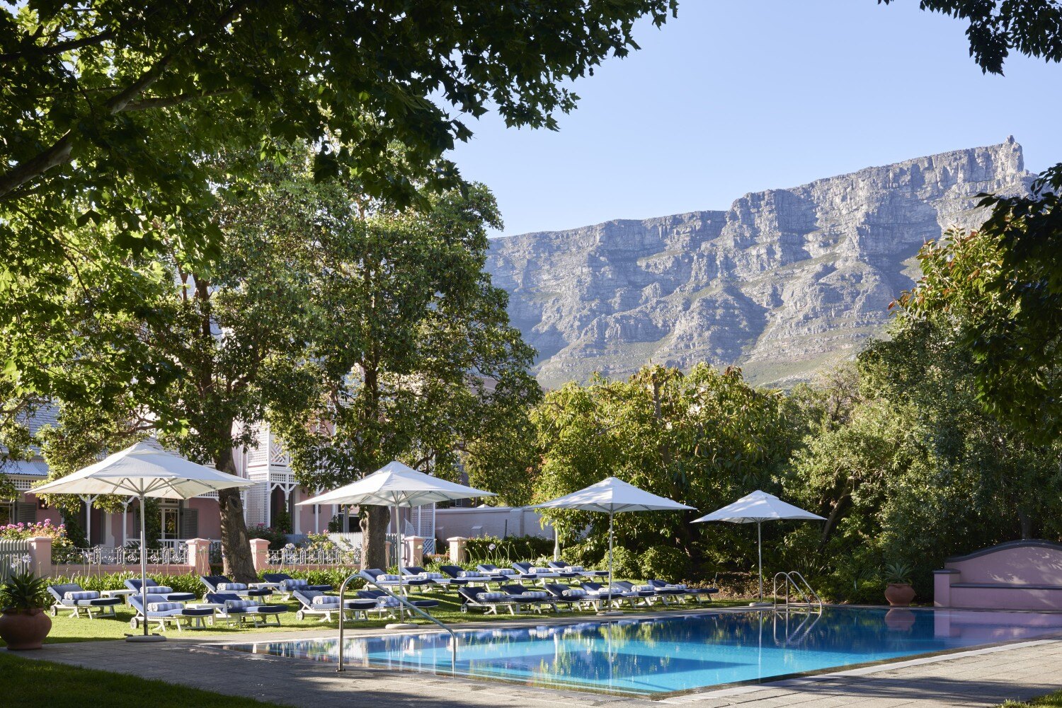 Pool mit Sonnenschirmen, im Hintergrund thront der Tafelberg.
