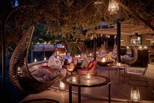 Eine Terrasse mit großem Baum wird am Abend von vielen Laternen erleuchtet.