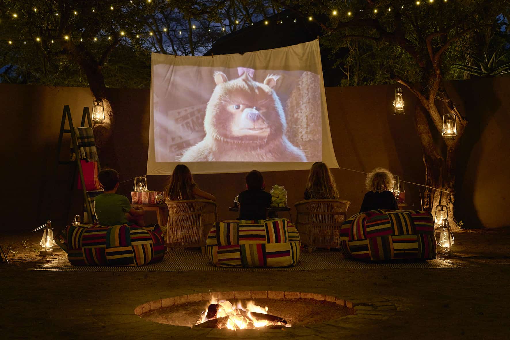 Kinder sehen sich am Abend im Freilichtkino einen Kinderfilm an.