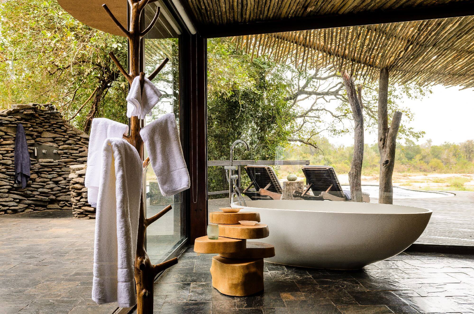 Spa-Bereich auf einer Terrasse mit Handtüchern und einer freistehenden Badewanne.