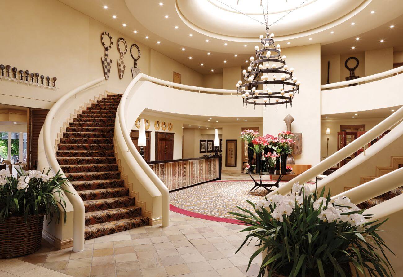 Elegantes Treppenhaus in der Lobby eines Hotels mit Kronleuchter in der Mitte.