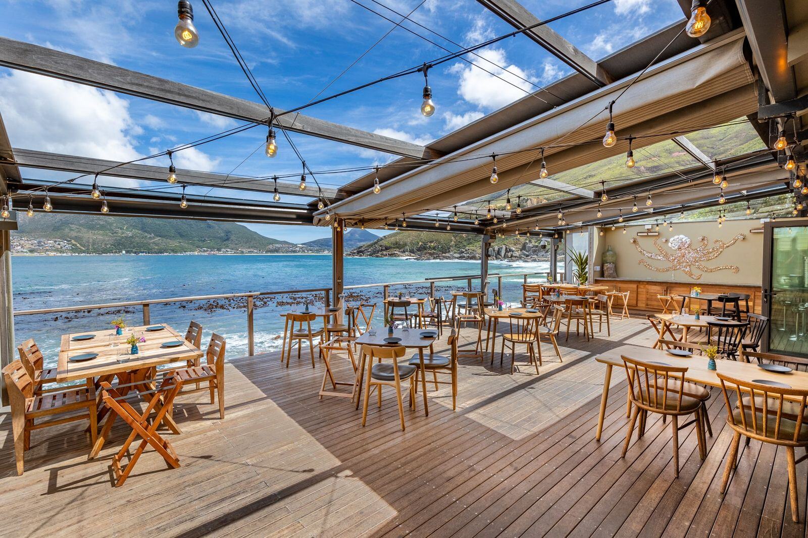 Restaurant eines Hotels auf einer Holzterrasse direkt am Meer.