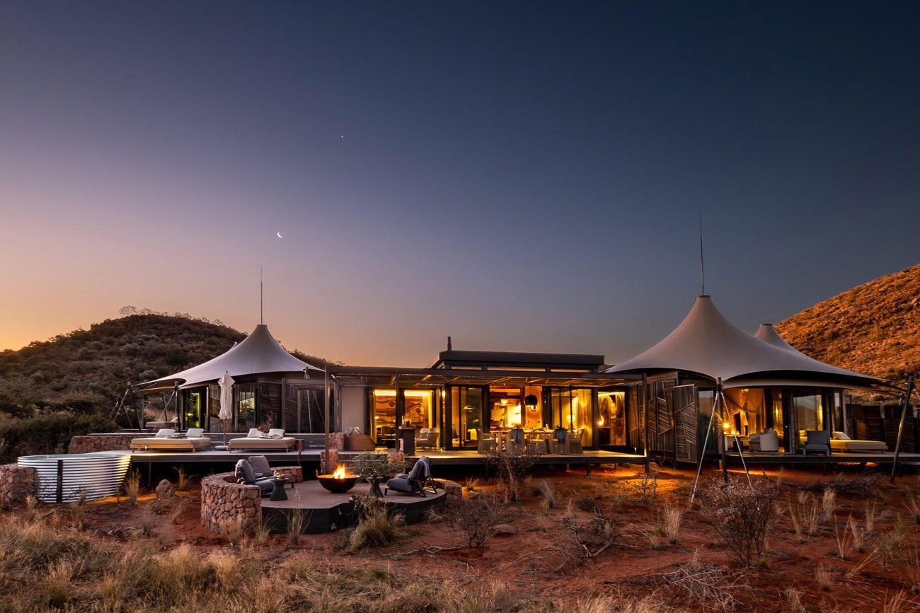 Beleuchtetes Zeltcamp in der Kalahari zur blauen Stunde.