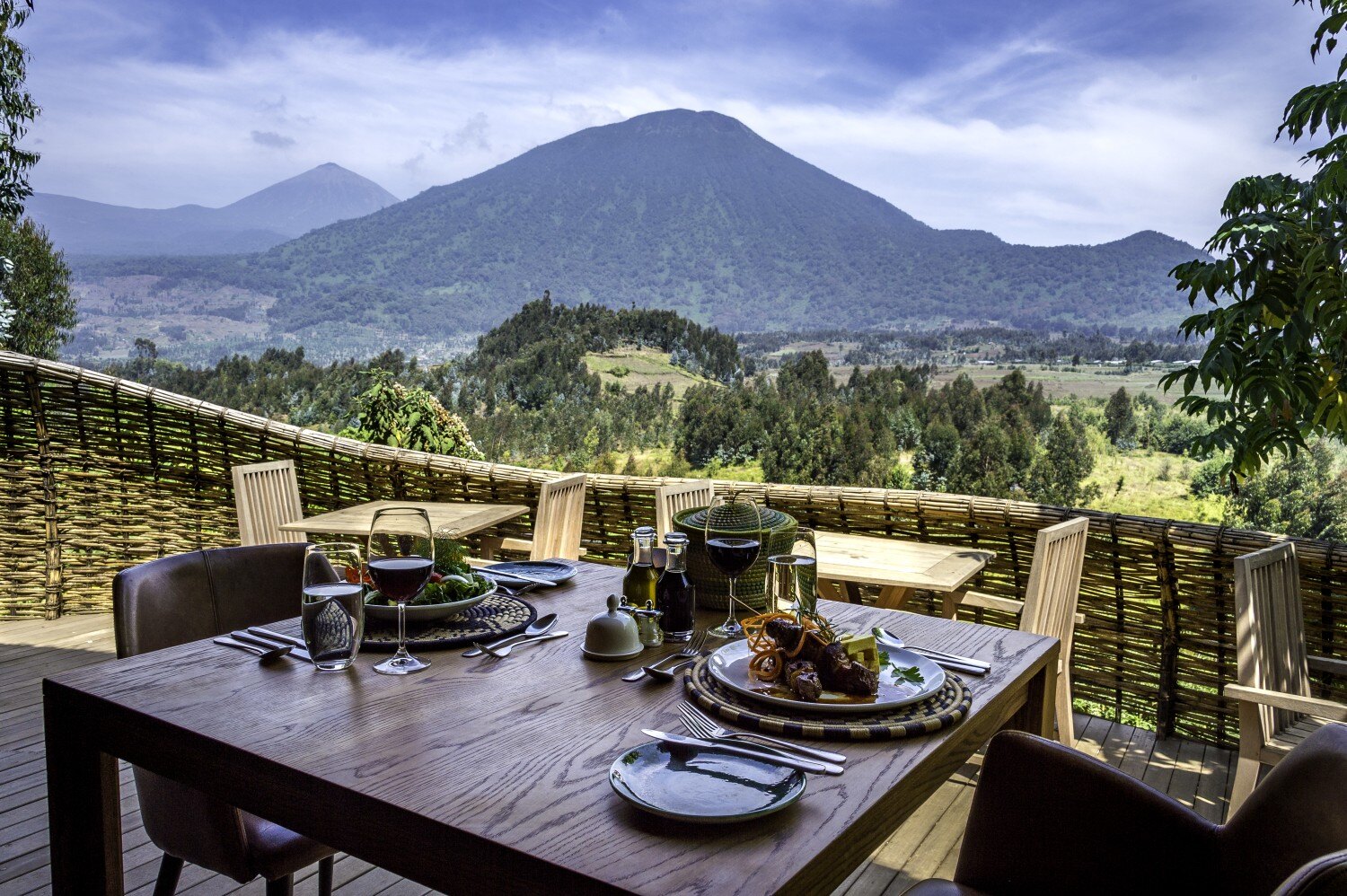 Ein gedeckter Tisch steht auf einem Balkon, die Aussicht zeigt die fruchtbare Berglandschaft.