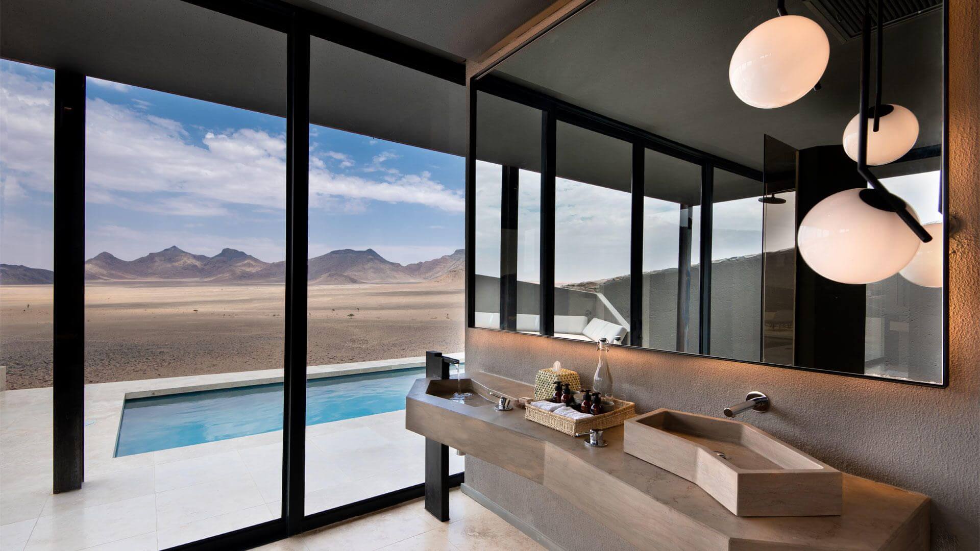 Luxuriöses Badezimmer mit Blick auf den Pool und die dahinterliegende Wüstenlandschaft.