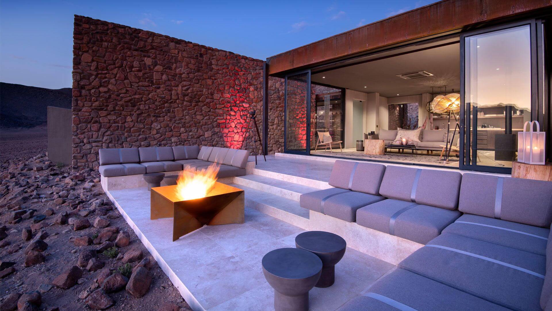 Terrasse mit Feuerschale und gemütlichen Sitzbänken in der Abenddämmerung.
