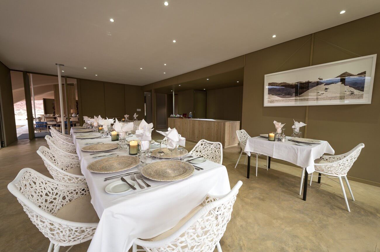 Speisezimmer mit einer lang gedeckten Tafel, alles in hellen Farben gehalten.