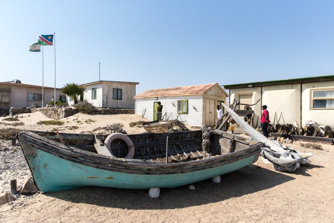Ein türkises Fischerboot steht an Land.