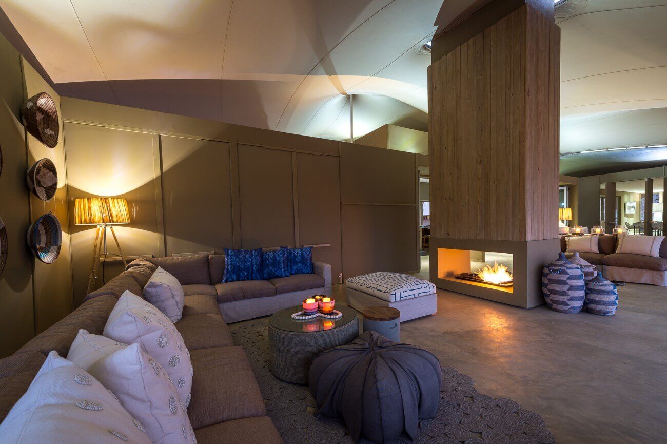 Gemütliches Kaminzimmer mit Sofas und vielen Kissen.
