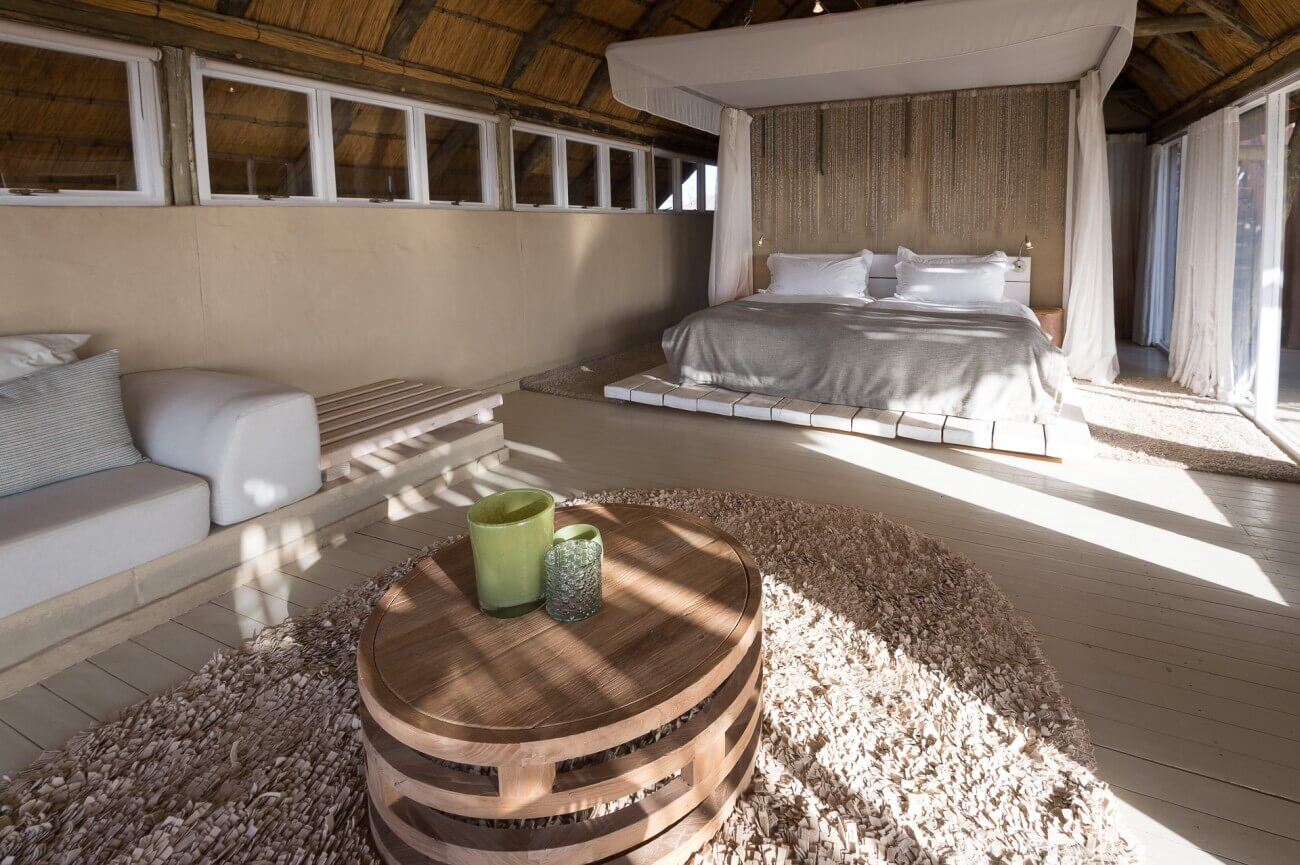 Helle, freundliche Inneneinrichtung mit Himmelbett, Sofa, Teppich und Tisch.