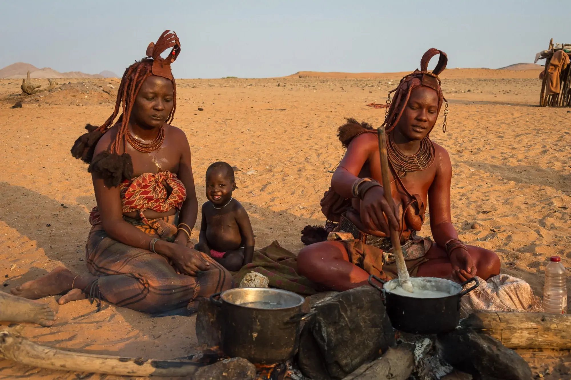 Himba-Frauen im Kaokoveld, Namibia, kochen über Feuer.