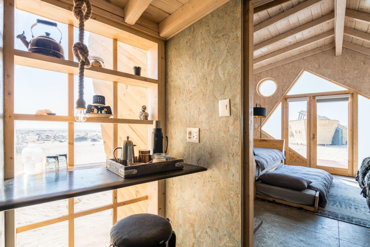 Inneneinrichtung mit Regalen an der Fensterfront und einem Blick ins Schlafzimmer.