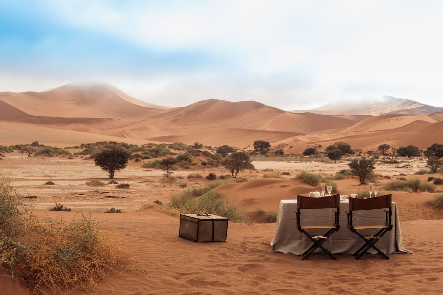 Ein gedeckter Tisch mit zwei Stühlen steht in der Wüstenlandschaft.