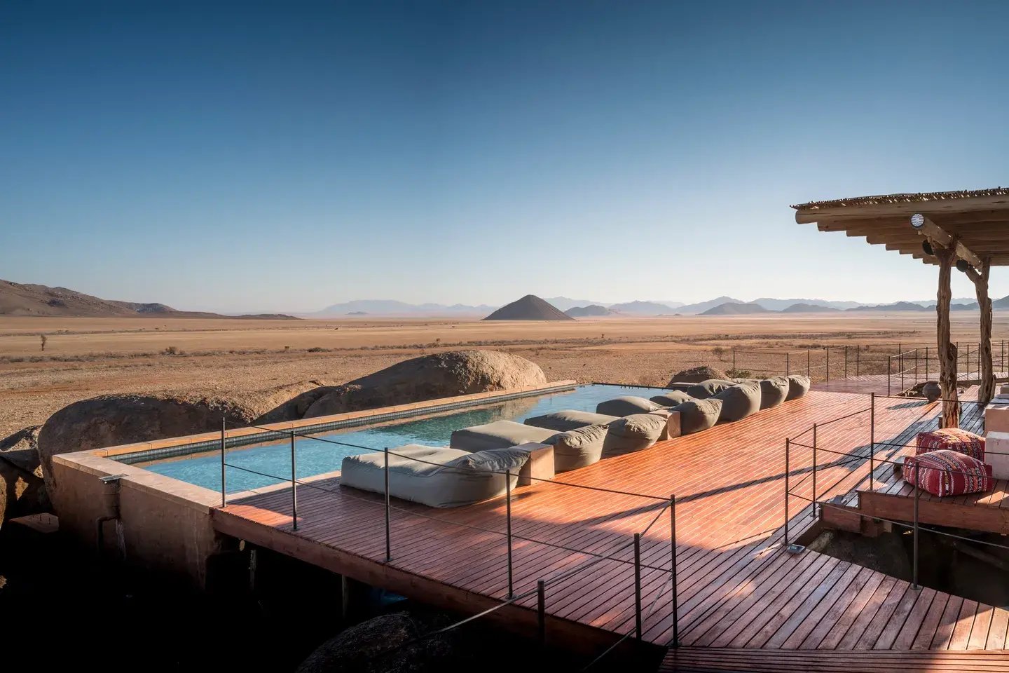 Poolarea mit vielen Liegen und einem weiten Blick in die Wüste.
