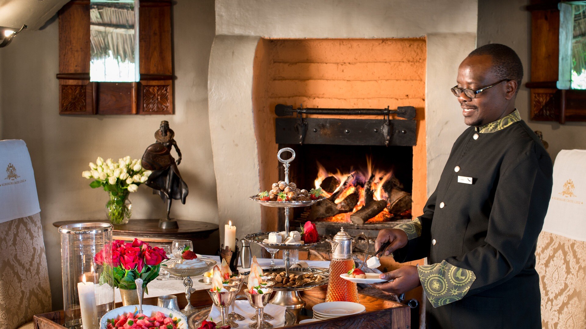 Ein Butler steht neben einem Tisch mit Süßigkeiten und bereitet diese vor.