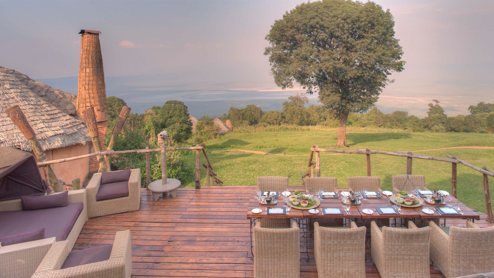 Terrasse mit Esstisch und Blick in einen Garten mit Baum.